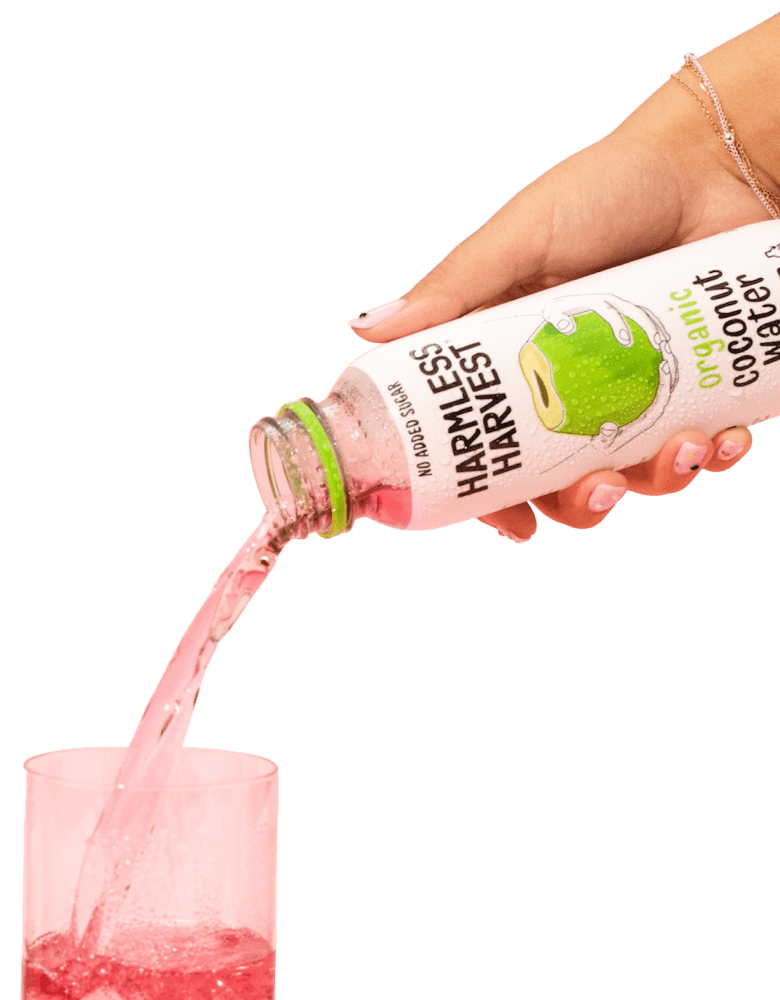 Hand pouring Organic Coconut Water into glass