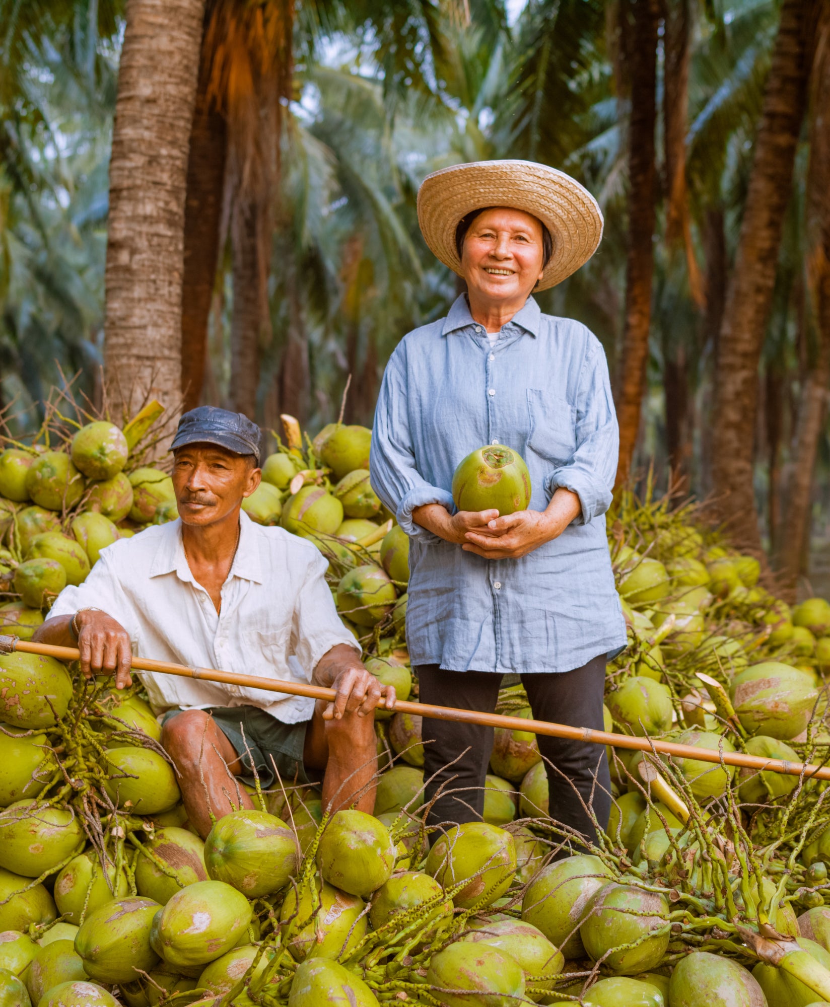 Coconut farmers in Thailand sitting amongst freshly harvested coconuts.